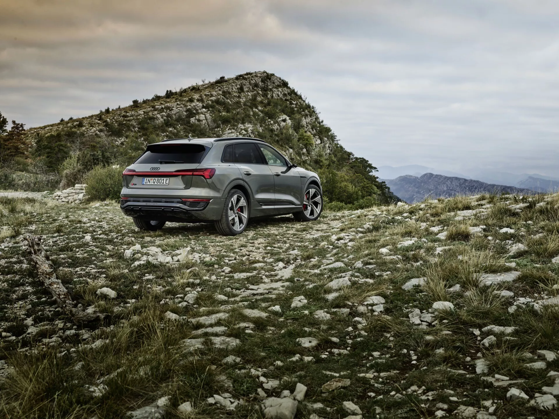 Audi Q8 e-tron 2023 com acabamento metálico posicionado em terreno natural acidentado exibindo capacidades off-road, design esportivo e prático com luzes traseiras LED, rodas de liga leve e recursos tecnológicos avançados