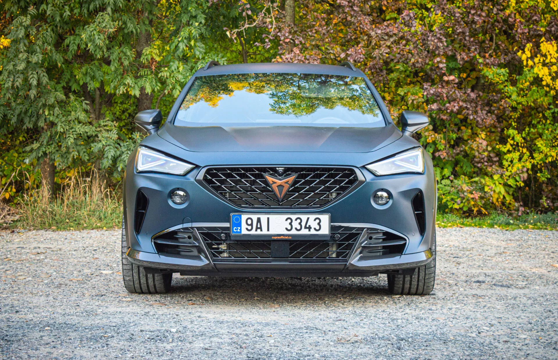 Vista frontal do Cupra Formentor 2020 exibindo design moderno, grade grande com emblema, padrão geométrico na grade, faróis LED elegantes, luzes de nevoeiro, para-choque dianteiro esportivo com grandes entradas de ar, linhas de caráter no capô, placa de licença europeia central e spoiler labial para desempenho aerodinâmico.