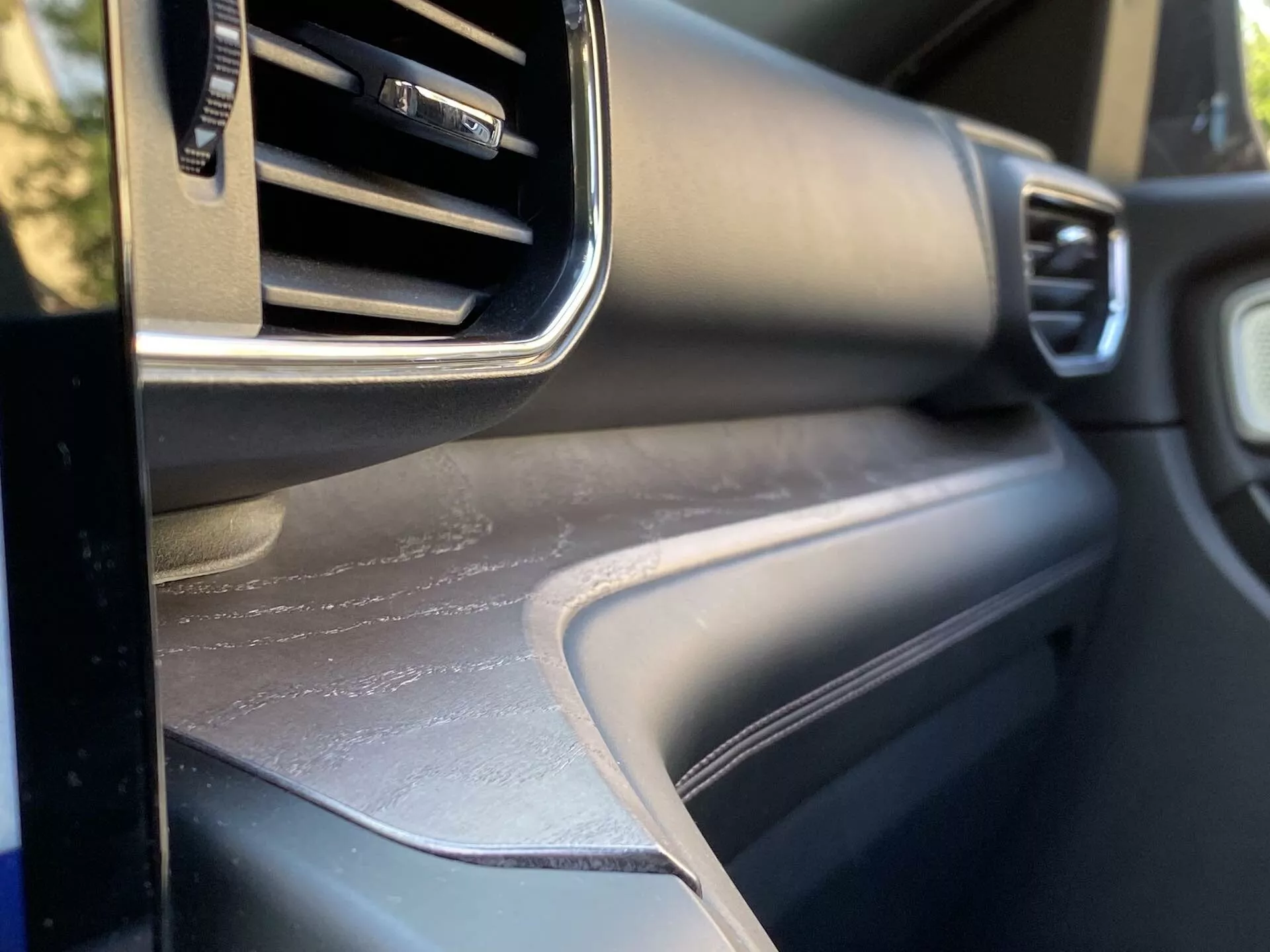 Vista aproximada do interior do Ford Explorer 2019, focada na área do painel lateral do passageiro com ventilação de ar condicionado ajustável, acabamento metálico, superfície texturizada do painel e painel de porta correspondente, mostrando o design interior e a qualidade dos materiais do veículo.