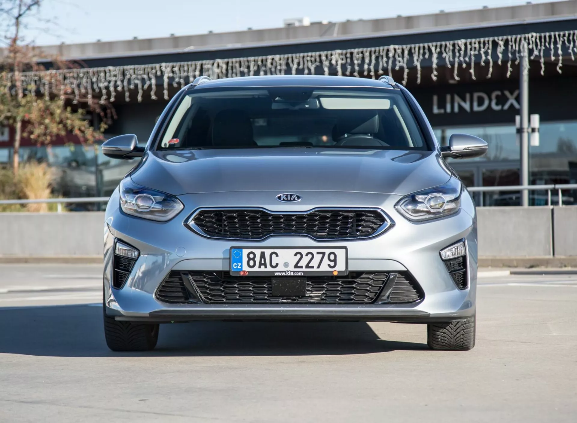 Modelo Kia Ceed 2009 em prata metálico, visão frontal e lateral com luz diurna clara, mostrando rodas de liga leve e design aerodinâmico