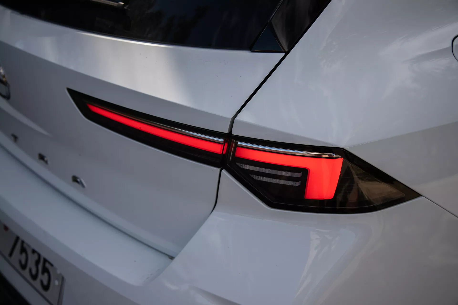 Close-up da luz traseira esquerda do Opel Astra 2022, destacando design LED elegante e integração na carroceria branca com estética esportiva