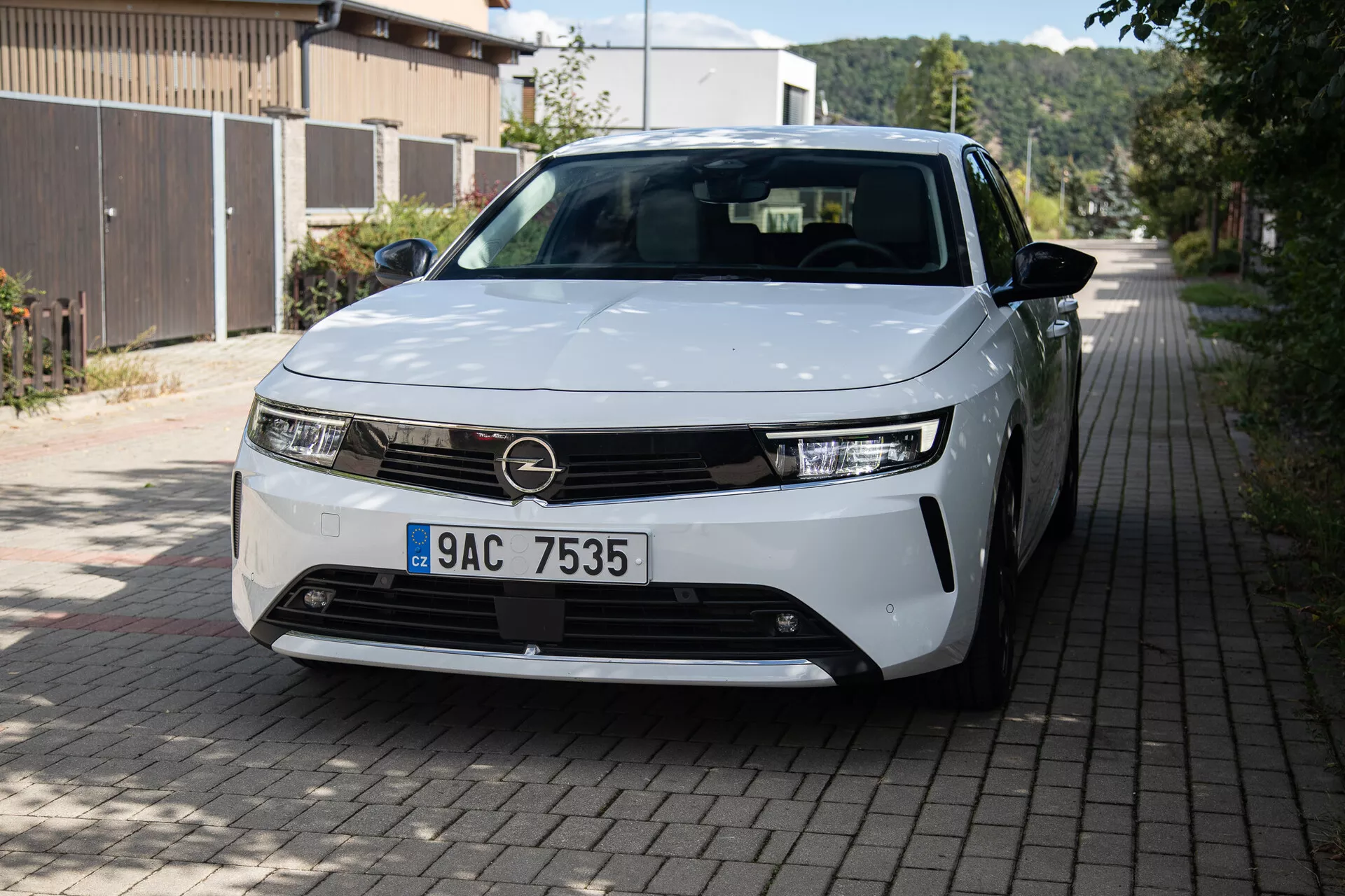 Vista frontal e de três quartos do Opel Astra 2022 destacando faróis LED, design de grade minimalista, rodas de liga levemente visíveis e painéis de carroceria elegantes em uma rua residencial europeia