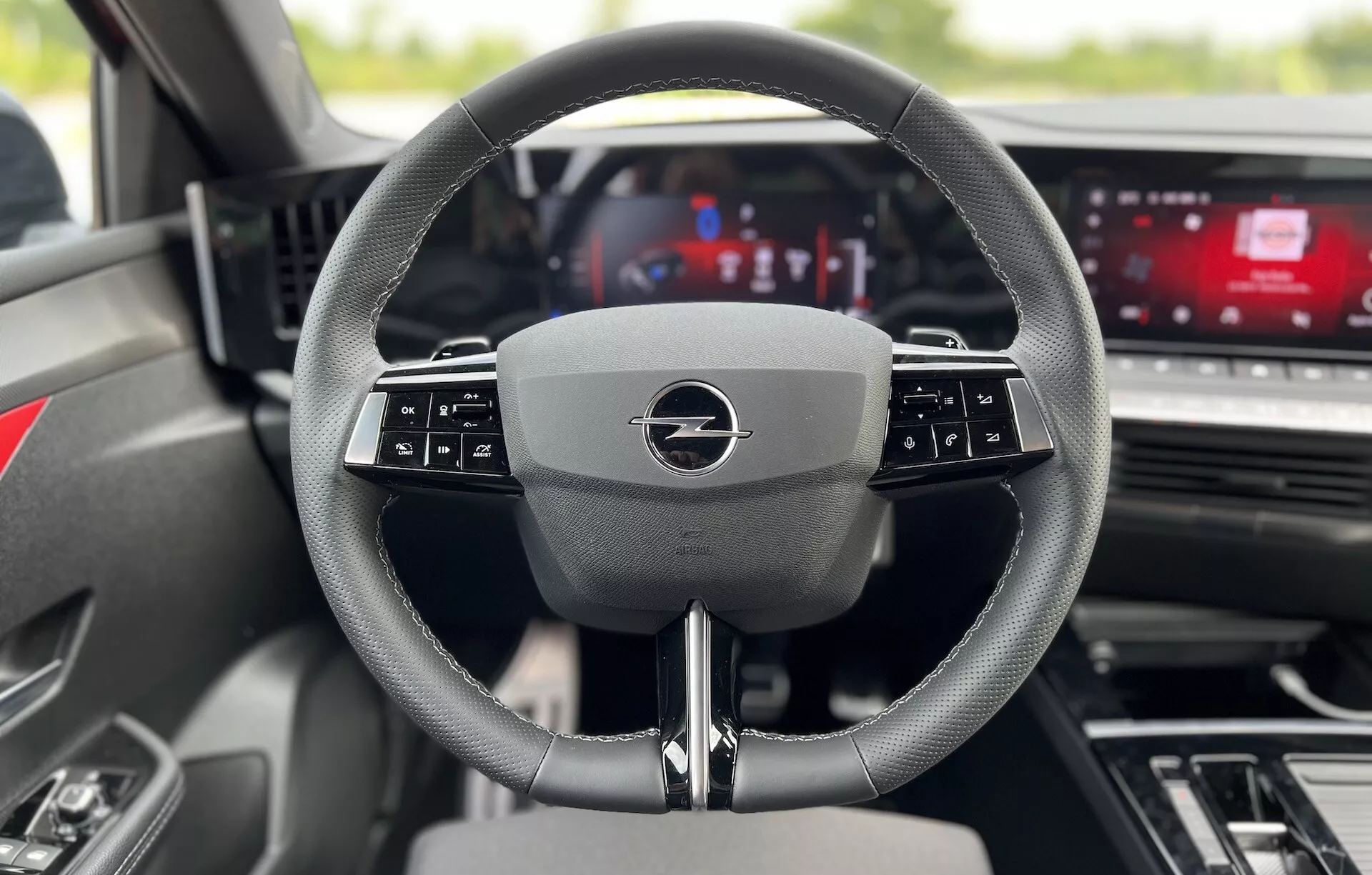 Vista interior do Opel Astra 2022 do assento do motorista focada no volante multifuncional moderno e painel de instrumentos digital