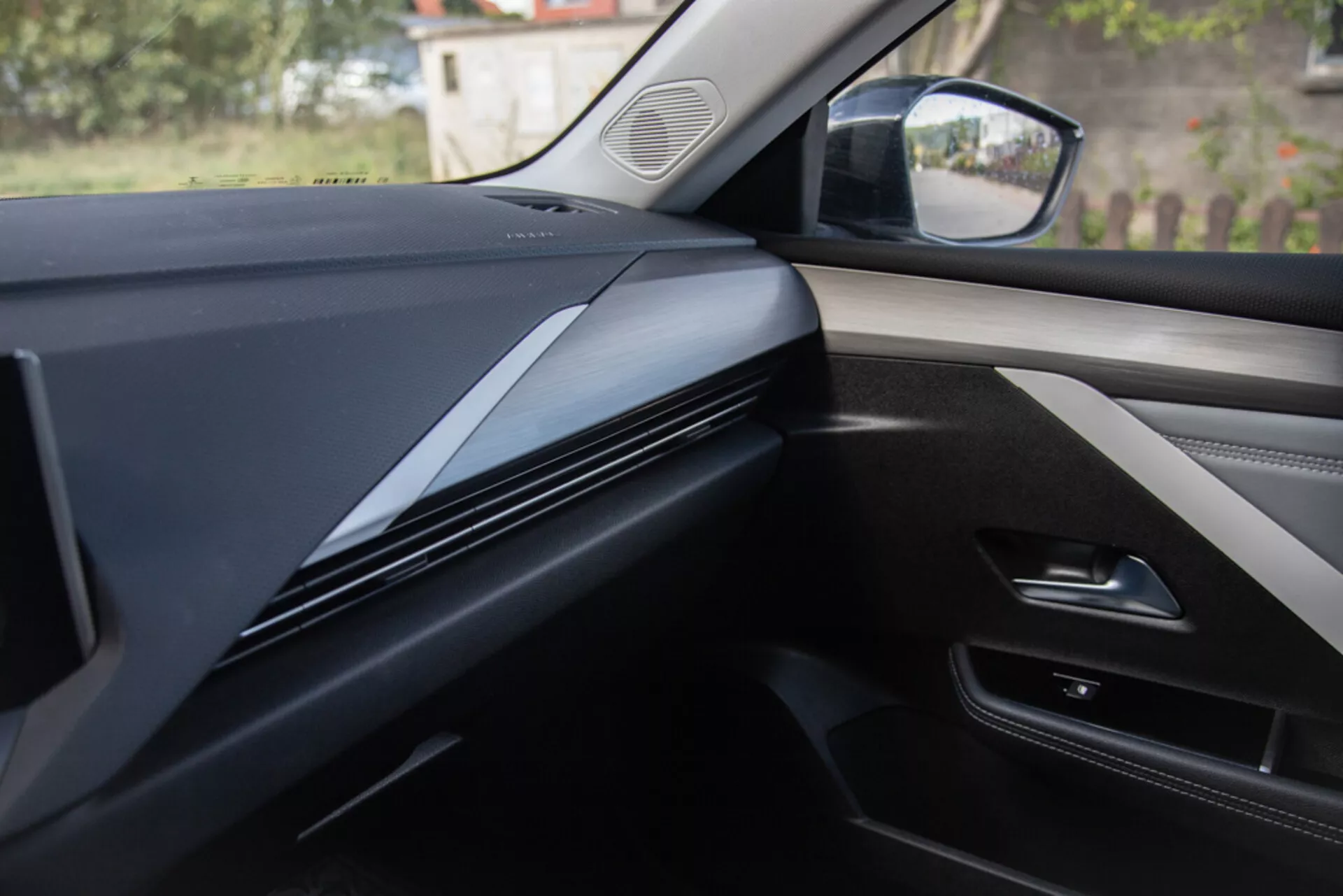 Vista interior a partir da perspectiva do assento do passageiro mostrando o design do painel, acabamento e painel da porta em um Opel Astra 2022, com linhas contornadas escuras e elegantes com foco na textura do material e potenciais integrações tecnológicas