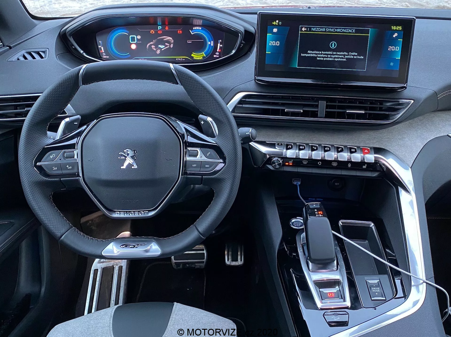 Vista interior de um Peugeot 3008 2021 a partir da perspectiva dos bancos traseiros que mostra a cabine dianteira: volante multifuncional moderno com design inferior achatado e botões de controle, painel de instrumentos digital, console central elevado com botão de seletor de marchas e freio de estacionamento eletrônico, sistema de infotainment com tela sensível ao toque independente, aberturas de ar retangulares com controles de clima, design de interiores elegante com material tipo couro, acentos metálicos, acabamento em preto brilhante, conectividade USB, indicações de transmissão automática, porta-copos e espaço de armazenamento.