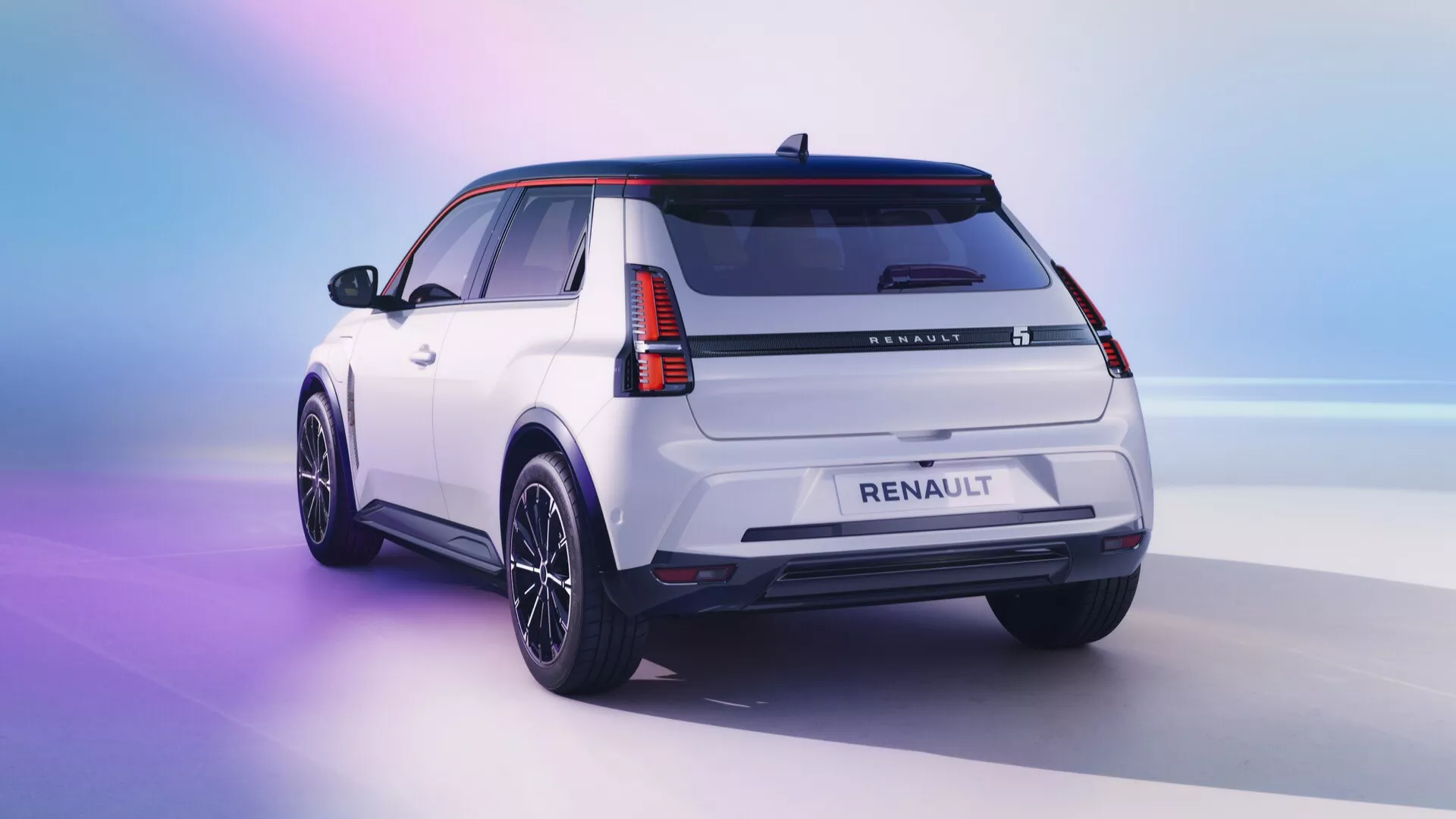Vista traseira de três quartos de um SUV Renault R5 2024 branco sobre um fundo gradiente que passa de rosa para azul, destacando o design moderno do veículo com faróis traseiros em LED, revestimento corporal preto, rodas de liga leve de acabamento escuro, spoiler de teto e antena em forma de barbatana de tubarão, sob iluminação de estúdio.