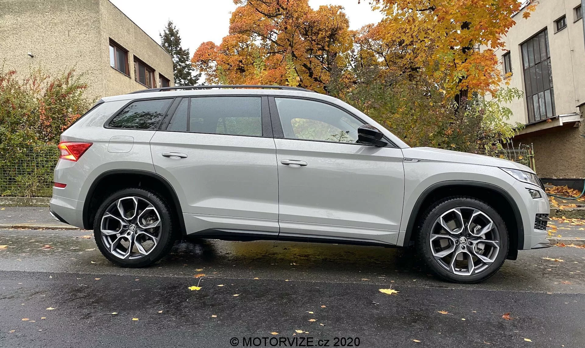 Perfil lateral de um SUV Skoda Kodiaq 2017 prateado capturado de um ângulo ligeiramente inclinado, enfatizando a roda dianteira e o para-lama. Mostra o comprimento do veículo e elementos de design, como faróis modernos, rodas de liga leve multi-raios, linha de caráter proeminente, trilhos de teto e luzes traseiras elegantes. Fundo neutro com iluminação uniforme. Crédito da foto: MOTORVIZE.cz 2020.