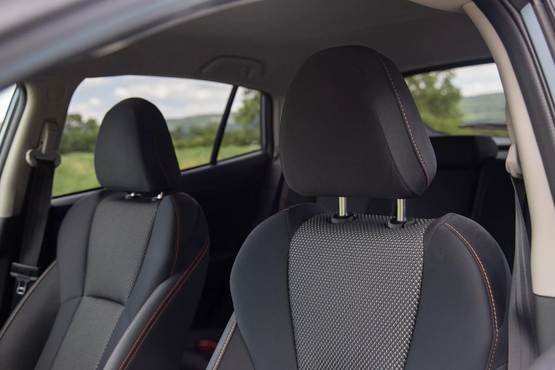 Vista interior do Subaru XV 2021 com assentos de couro preto com inserções de tecido padronizado e costura laranja distintiva, focando em conforto e design da perspectiva de um passageiro traseiro