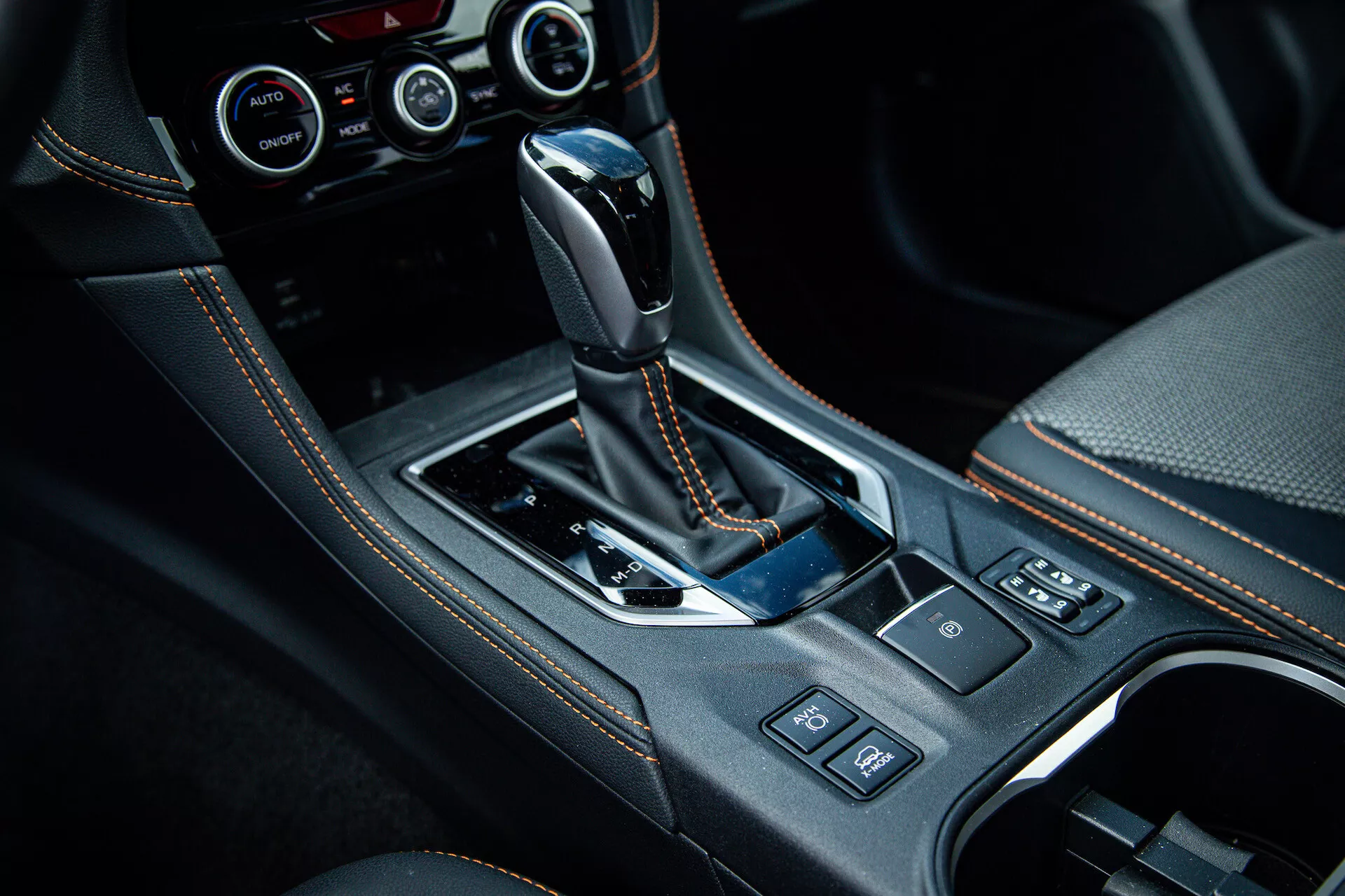 Console central do Subaru XV 2021 com alavanca de câmbio automática revestida em couro, painel em preto brilhante, detalhes cromados, porta-copos, botões de controle e sistema de controle climático avançado visível em foto de interior de alta qualidade