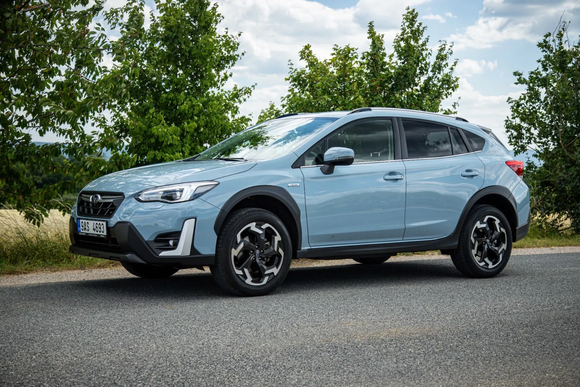 SUV crossover Subaru XV 2021 azul claro estacionado no asfalto exibindo perfil lateral, rodas de liga leve pretas distintas, luzes traseiras LED, alta distância do solo para uso urbano e leve fora de estrada, e características de segurança modernas