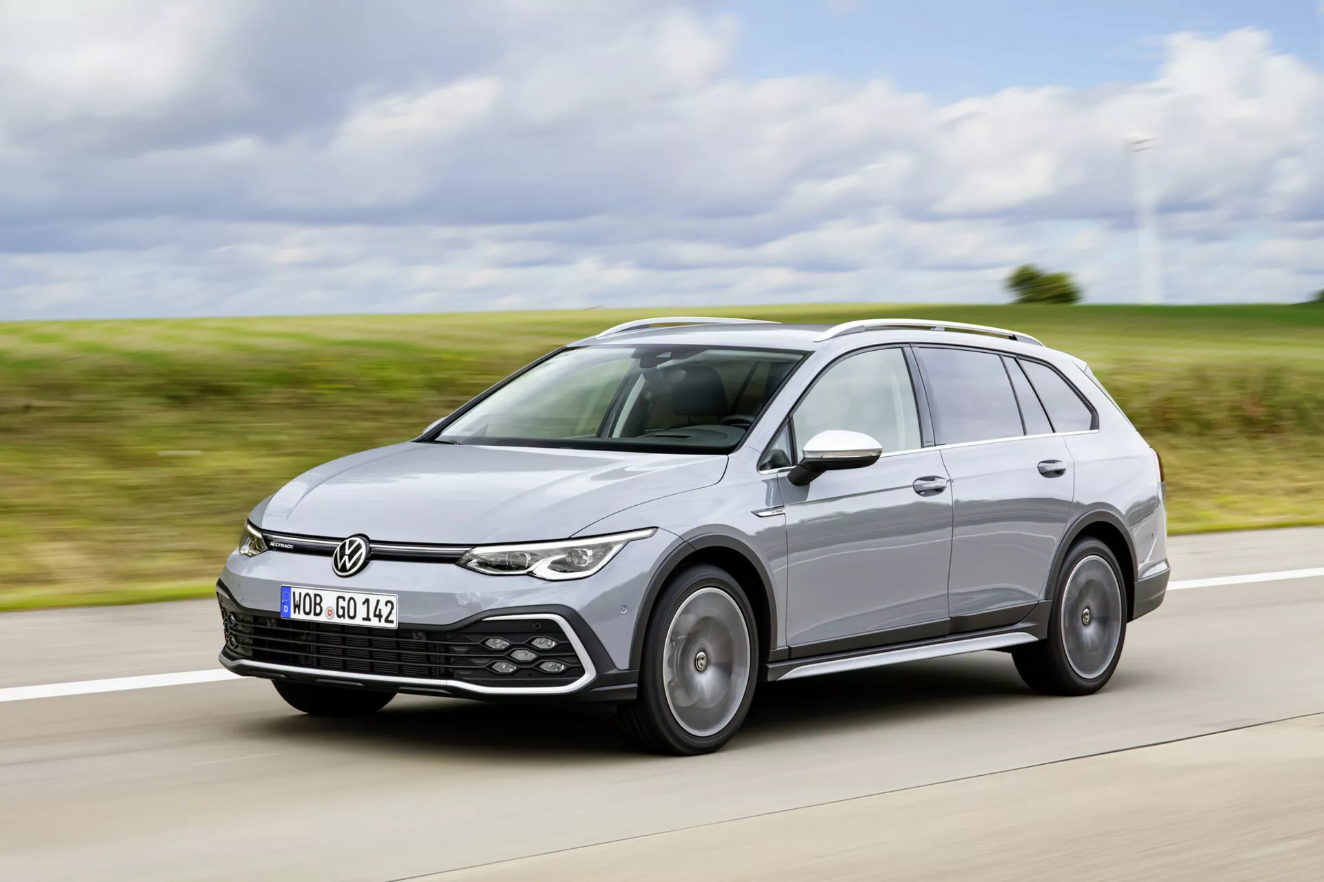 Volkswagen Golf Alltrack 2017 em movimento em uma rodovia, exibindo seu design moderno de perua, faróis LED, sensores de assistência de estacionamento e sistema de trilhos de teto de um ângulo frontal de três quartos.