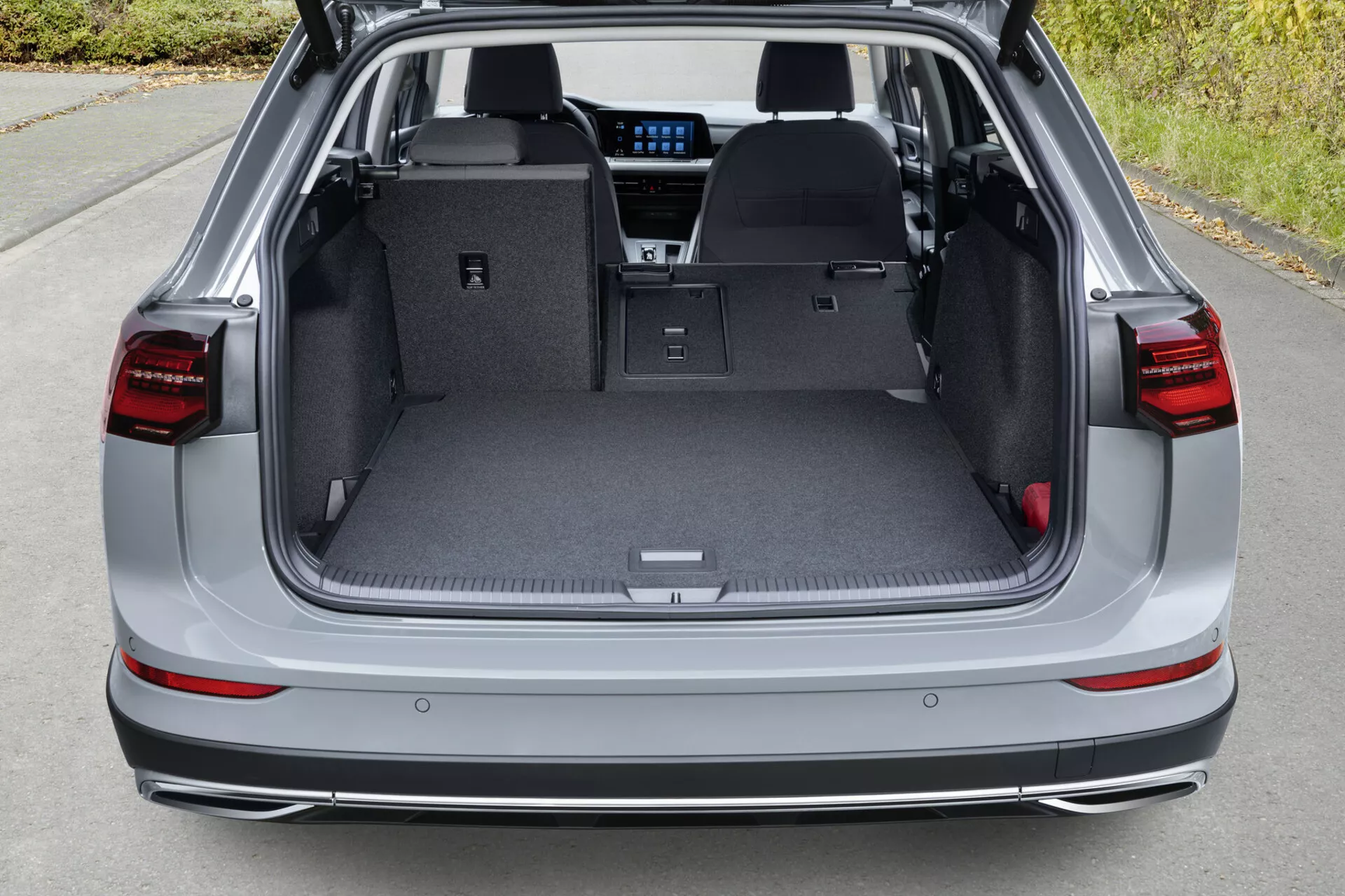 Espaço de carga traseira do VW Golf Alltrack 2017 mostrando porta-malas aberto com bancos traseiros rebatidos, interior cinza claro, tapete protetor, alça recuada, compartimentos de carga e vislumbre de recursos internos avançados